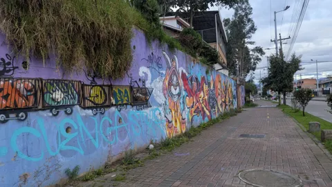 A colorful graffiti wall runs along a sidewalk and street.