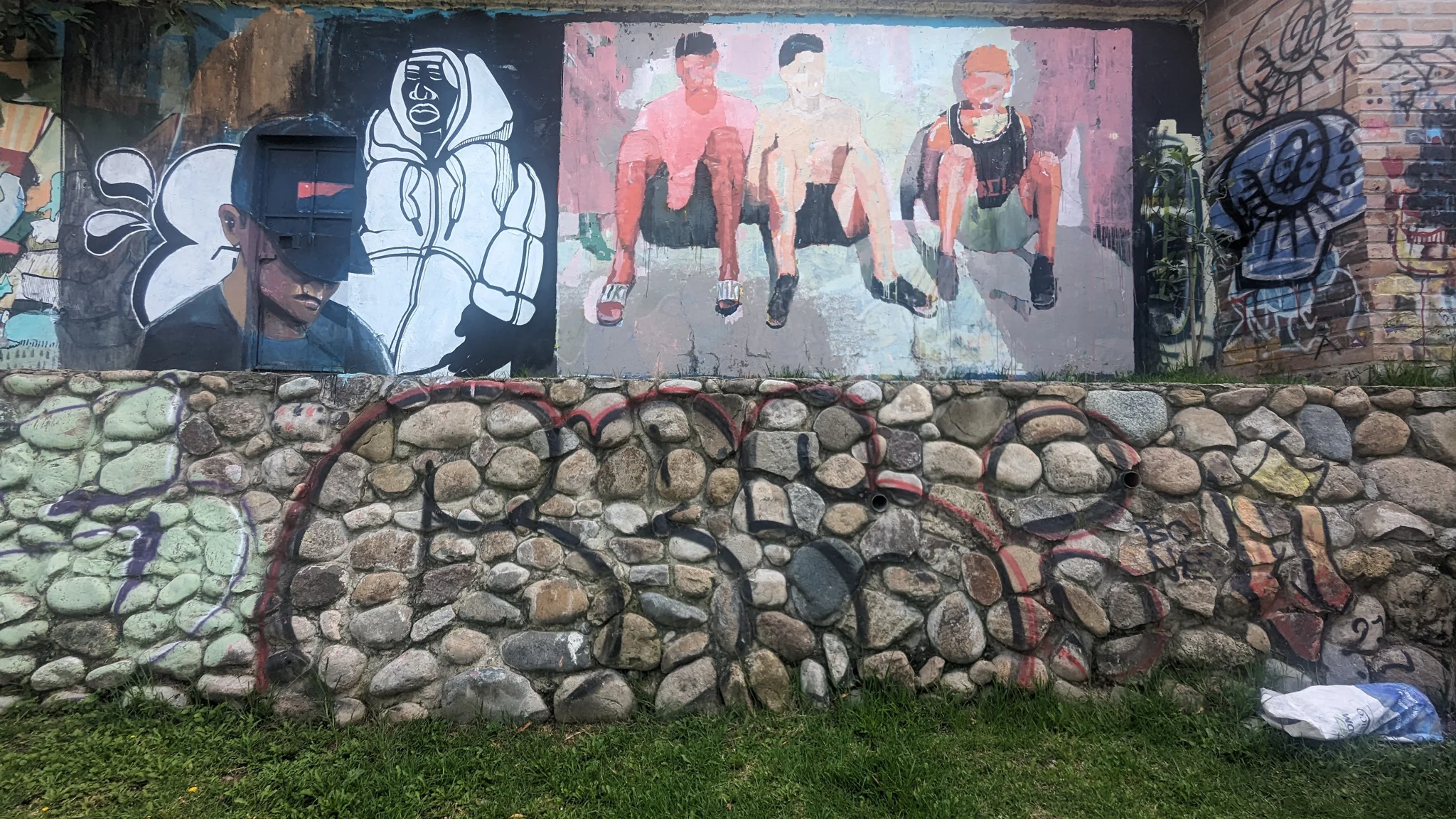 Painted portrait figures and graffiti cover a stone wall.