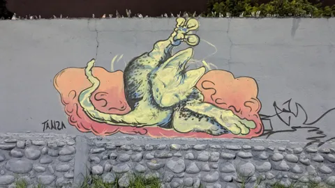 A cartoon-style mural of a character is painted on a wall.