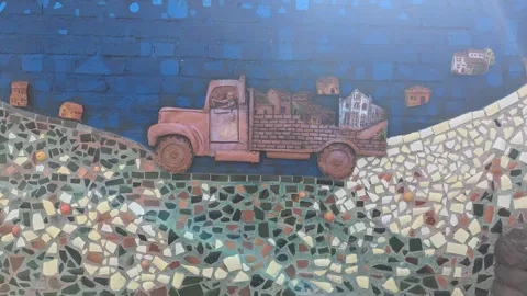 A mural of a truck is painted across a textured wall.
