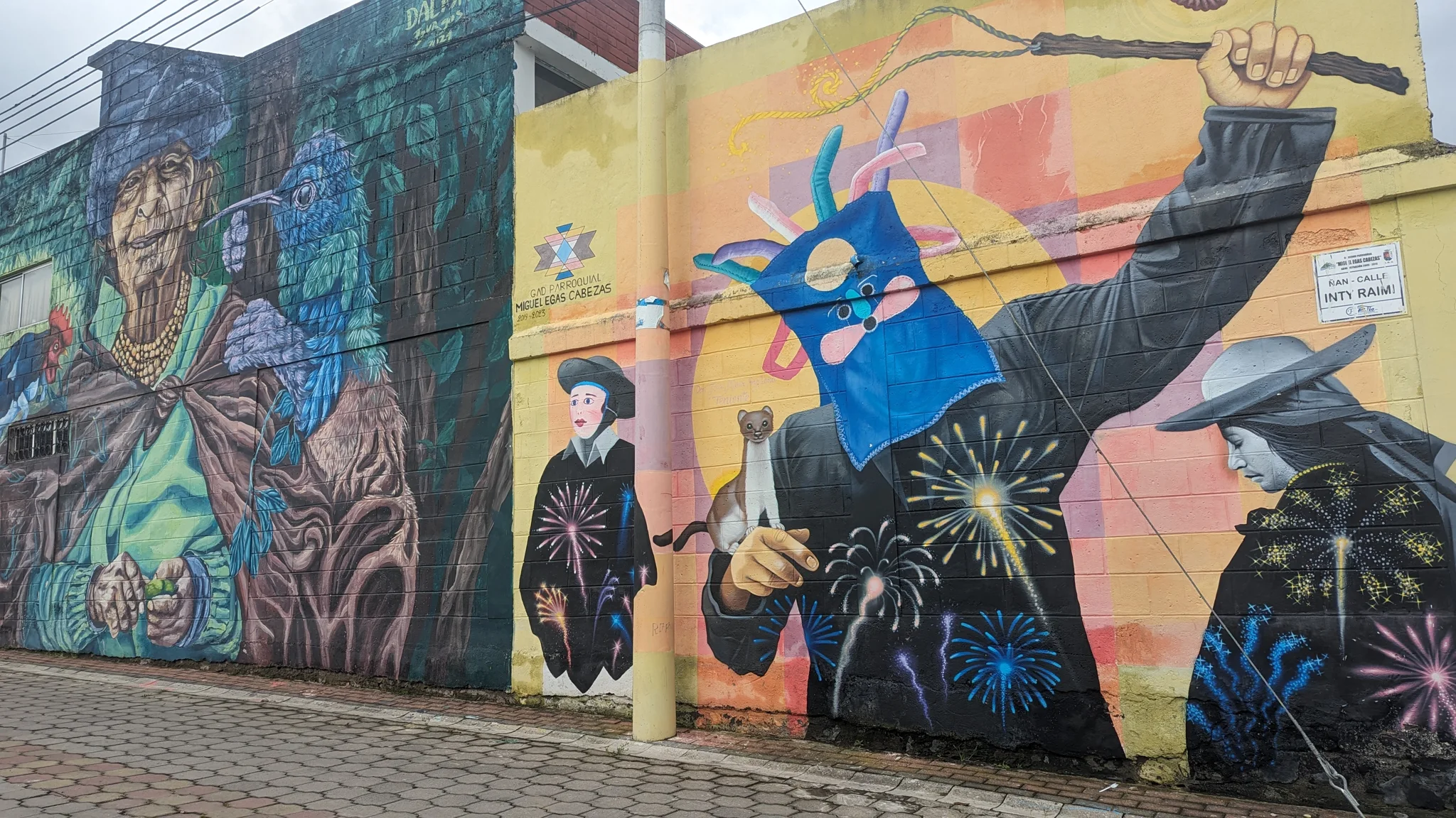 A colorful mural with birds and painted figures covers a long wall.