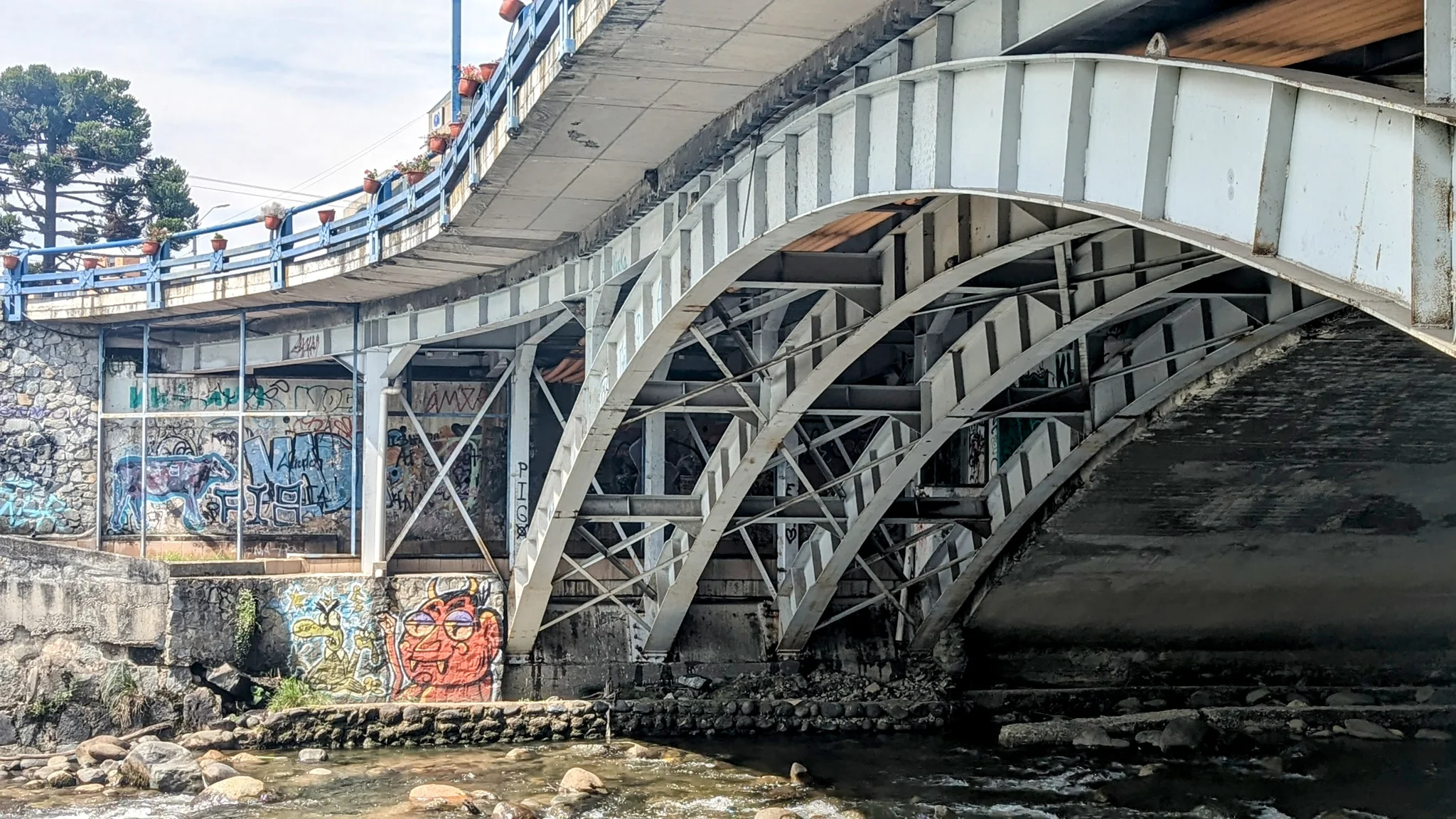 A steel arched bridge crosses a river in an urban setting.