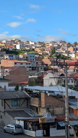 Cuenca neighborhood rooftops stacked across a hillside under clear sky.