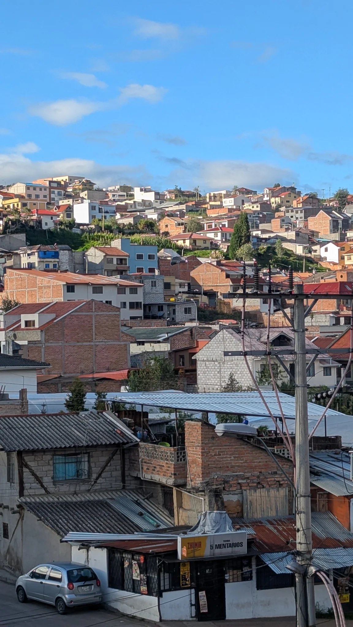Cuenca neighborhood rooftops stacked across a hillside under clear sky.