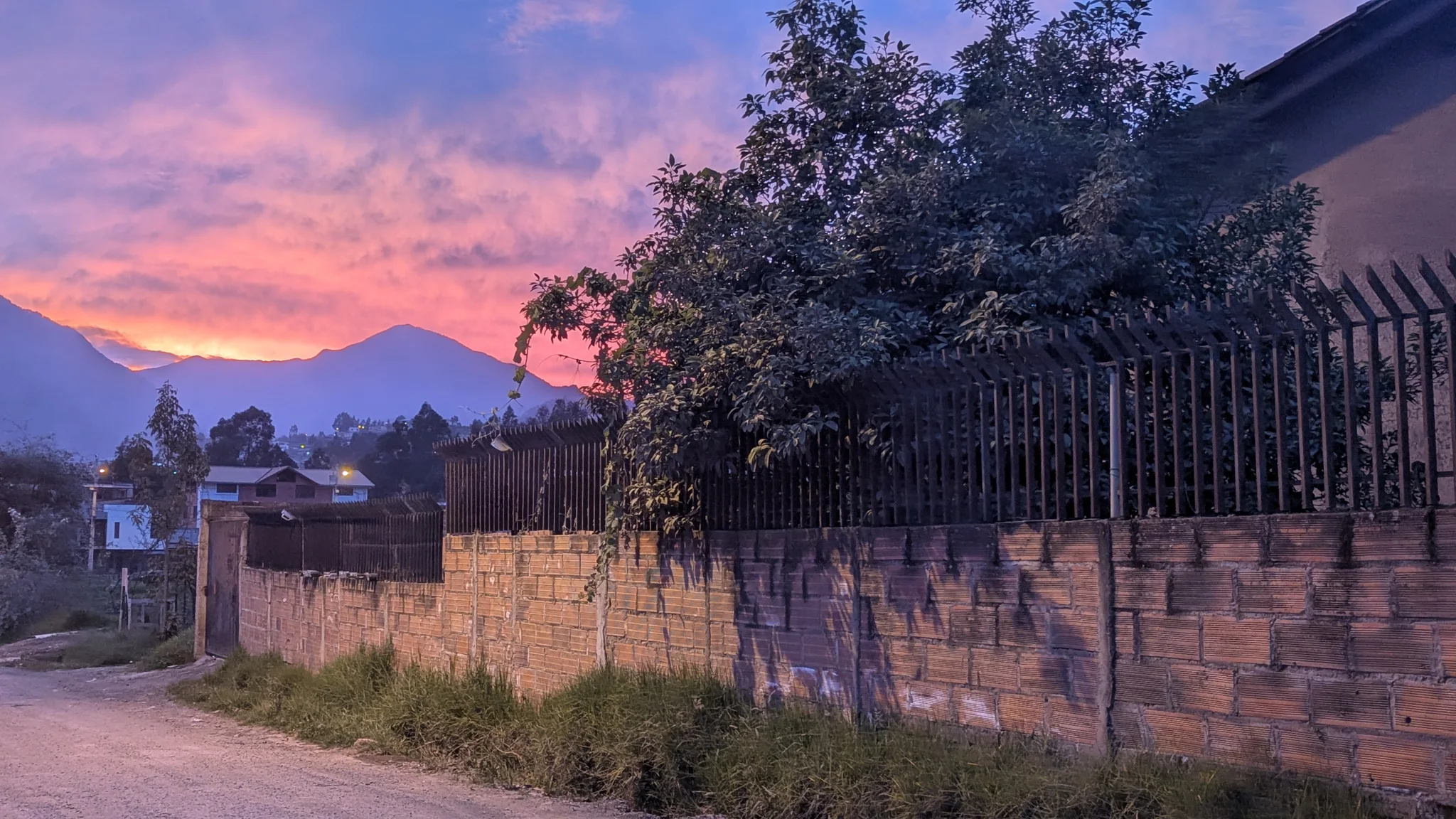 Purple and pink sunset clouds glow above dark trees and mountain silhouettes.