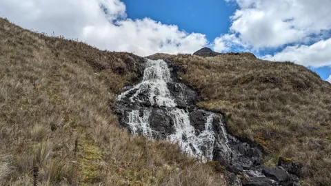 A waterfall crossing an open hillside
