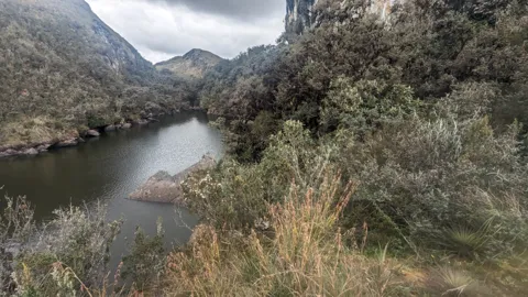 Lake below scrubby highland slopes. The water body is not securely named.