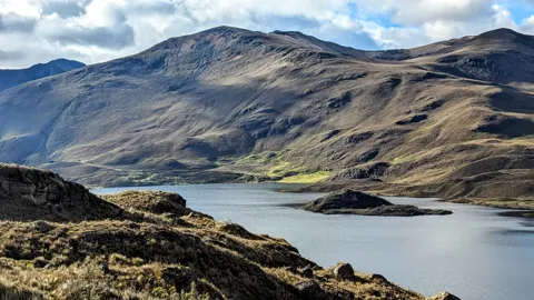 Sunlit slopes above pale water