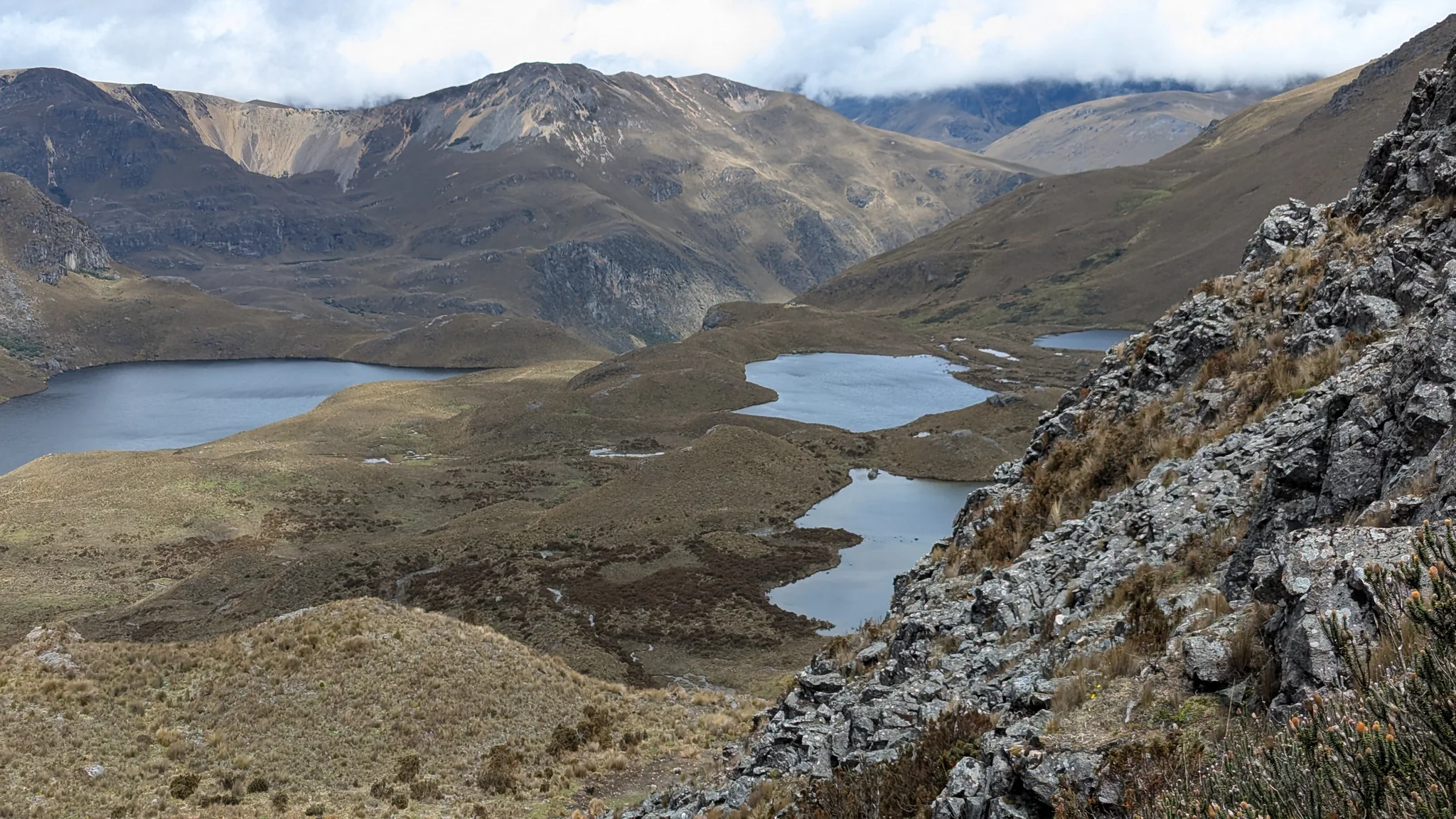 Several highland lakes and winding wetland margins spread across the basin below a rocky overlook. Individual lake names are unresolved.