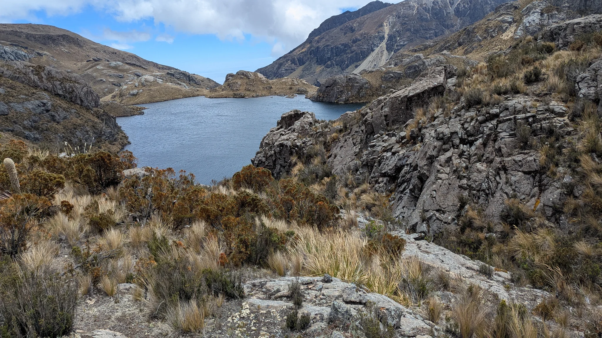Blue lake beyond a broken rocky shore. The water body is not securely named.