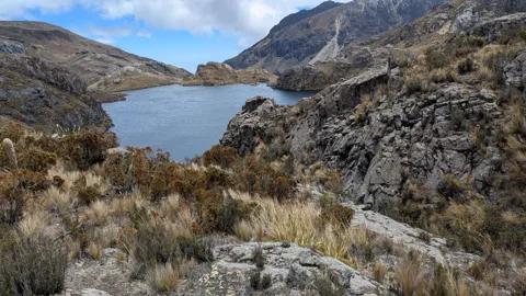 Blue lake beyond a broken rocky shore. The water body is not securely named.