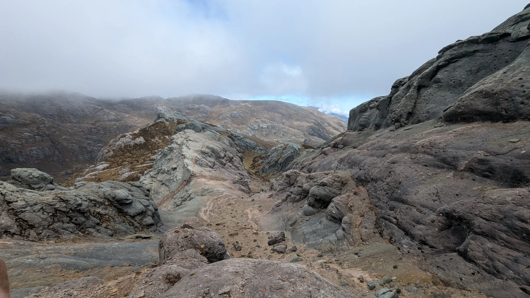 Smooth rock slabs form a winding corridor that disappears into highland fog.