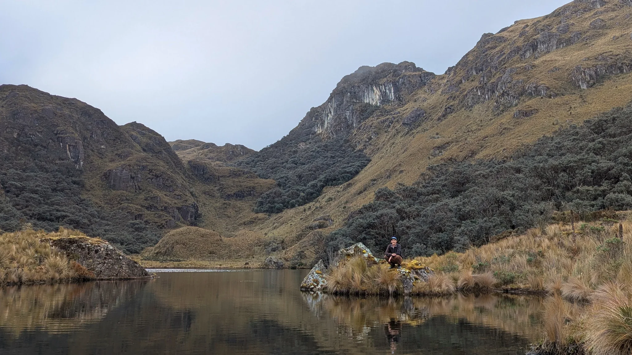 Hiker reflected beside an unnamed upper lake. The water body is not securely named.