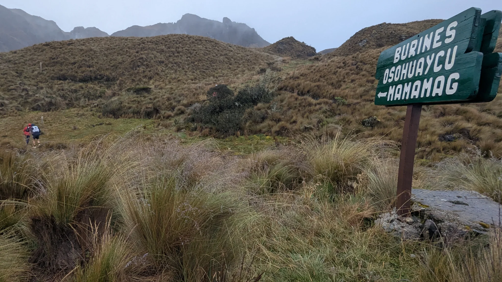 A wooden sign names Burines, Osohuaycu and Mamamag beside a narrow páramo path.