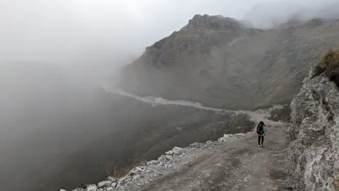 A walker beside a misty lagoon