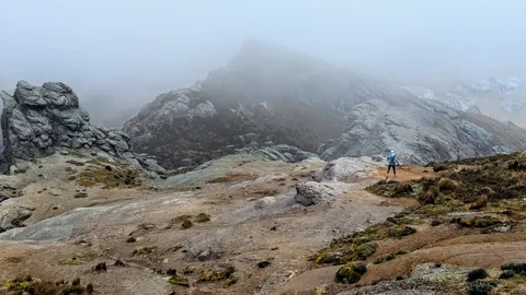 A hiker among rock slabs and low cloud
