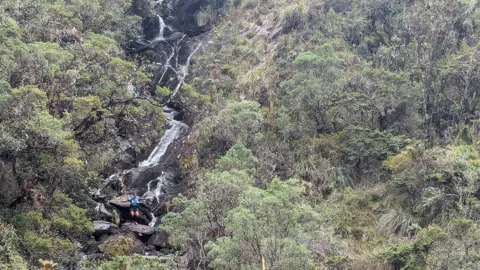 A waterfall framed by green slopes