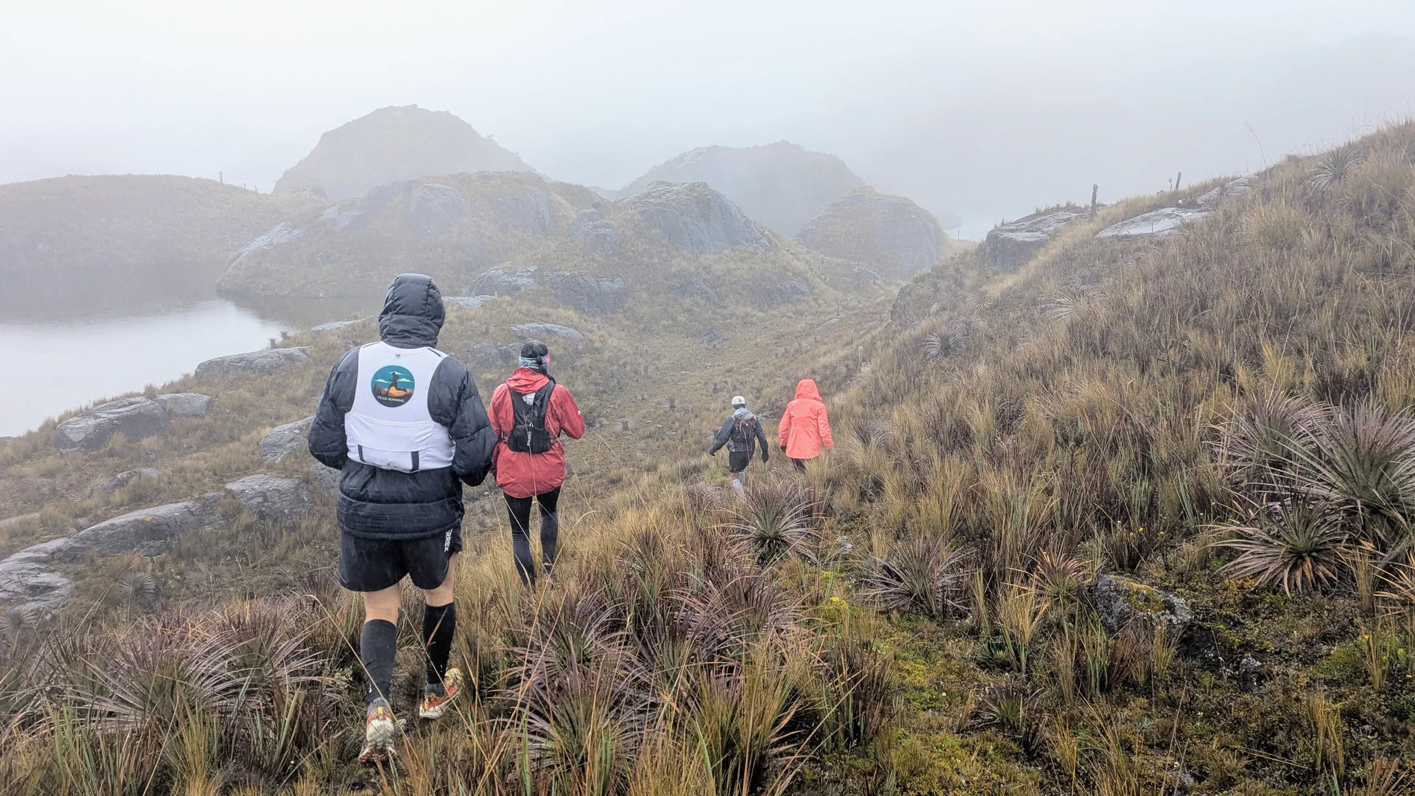 Hooded hikers above a misty lake. The water body is not securely named.