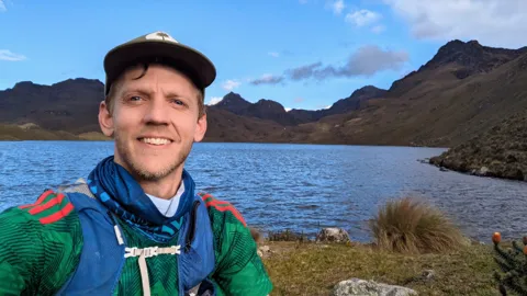 Runner selfie by mountain lake.